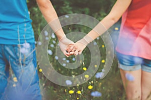 Teen couple holding hands in flower field