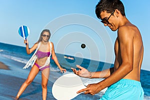 Teen couple playing smash ball beach tennis.