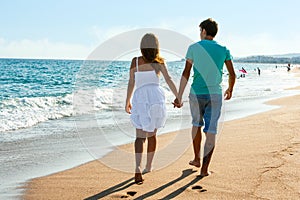 Teen couple walking away on beach.