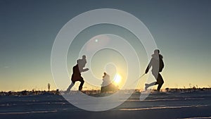 Teen daughter and mother pulling little son on sledge, running. Silhouette family playing in winter time. Active healthy