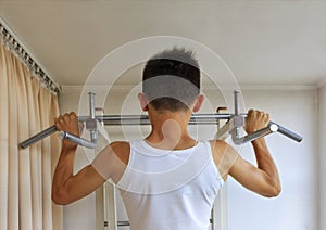 Teen doing exercises on the crossbar in the home sports corner