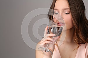 Teen drinking water from a bocal. Close up. Gray background photo