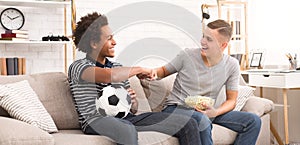 Teen fans making fist bump while watching soccer