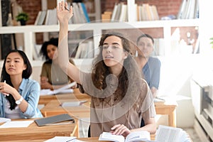 Teen female college university student raising hand during class