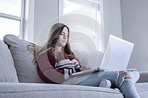 Teen female student studying on the couch doing school work from home