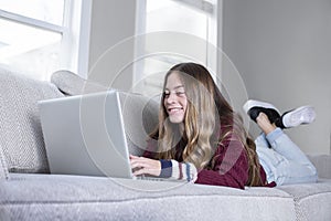 Teen female student web conferencing calling on the couch doing school work from home