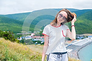 Teen girl 17s stands on the hill in sun glasses looking at the camera.