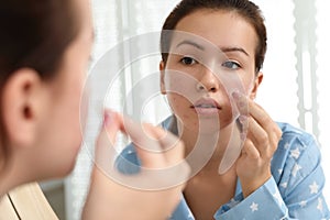 Teen girl applying acne healing patch near mirror photo