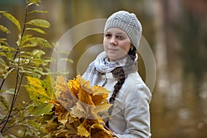 Teen girl in the autumn park with maple leaves