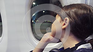 Teen girl aviation aircraft concept. young girl looks out the airplane sitting by the window. flight at night lifestyle