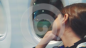 Teen girl aviation aircraft concept. young girl looks out the airplane sitting by the window lifestyle . flight at night