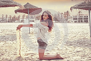 Teen girl on the beach playing with sand