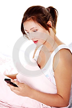 Teen girl in bed reading sms.