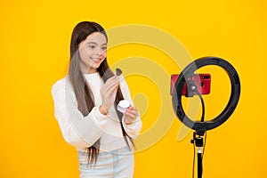 Teen girl blogger influencer use selfie led lamp and smartphone on tripod for making online video tutorial. Beauty blog