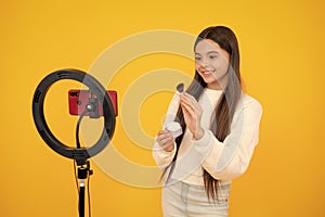 Teen girl blogger influencer use selfie led lamp and smartphone on tripod for making online video tutorial. Beauty blog