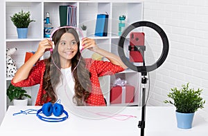 Teen girl blogger influencer use selfie led lamp and smartphone on tripod for making online video tutorial. Teenager