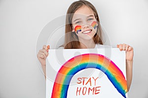 Teen girl drew rainbow and poster stay home. photo