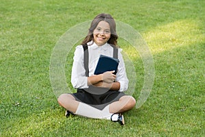 Teen girl with book on green grass. pretty child little girl read book. study literature for children. having fun with