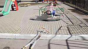 teen girl with a broken leg on crutches sits on a carousel in the playground.