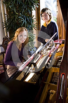 Teen girl with brother by piano