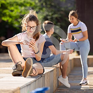 Teen girl carried away with smartphone outdoor
