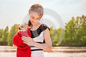 Teen girl and chihuahua dog in her arms. Beautiful girl near the river