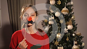 Teen girl with christmas props mask with red nose