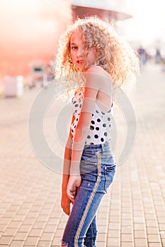 Teen girl on a city street posing in the rays of the evening sun