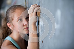 Teen girl climbing a rock wall indoor.
