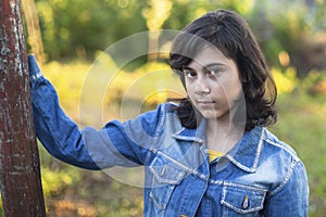 Teen girl in denim jacket portrait outdoors.