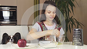 Teen girl with dog Papillon prepare cookies, knead the dough