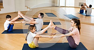 Teen girl doing yoga in pair with mom in studio