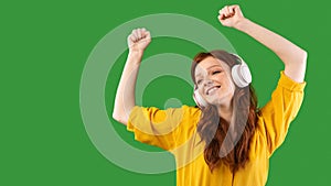 Teen Girl Enjoying Music In Earphones Dancing Over Green Background