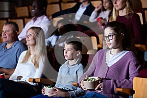 Teen girl with family watching film in movie theater