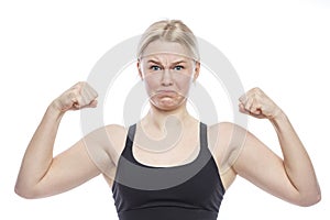 Teen girl funny shows her biceps. A cute blonde with freckles on her face in a sporty black top. Victory, activity and sport.