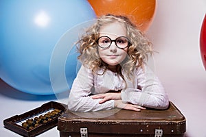Teen girl in glasses with wooden abacus on the background of large rubber balls.