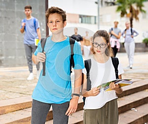 Teen girl going to lessons with classmate on autumn day