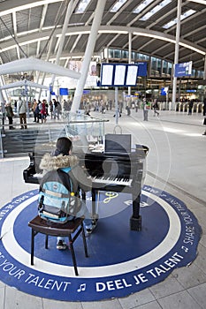 Teen girl at grand piano for everyone to use in hall of central