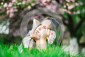 teen girl on grass in bloom. Beautiful little girl in pink dress with smiling happy face lying on green grass covered