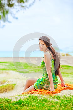 Teen girl in green sundress at beach looking over shoulder