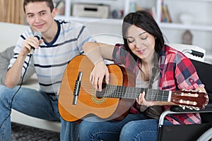 Teen girl handicapped guitarist playing with friend
