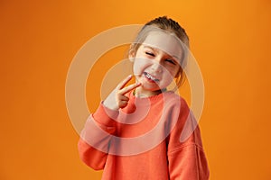 Teen girl happy positive makes peacel v-sign on yellow background