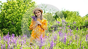 Teen girl in hat picking a bouquet of wildflowers in a meadow
