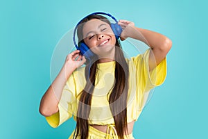 Teen girl in headphones listen to music. Wireless headset device accessory. Child enjoys the music in earphones on blue