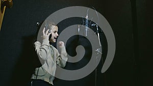 Teen girl in headphones singing into audio microphone professional studio music