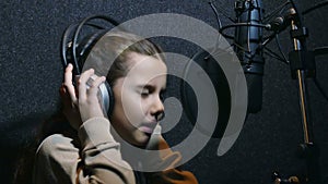 Teen girl in headphones singing into a microphone