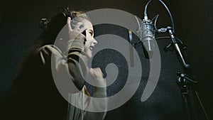 Teen girl in headphones singing into microphone audio professional studio music