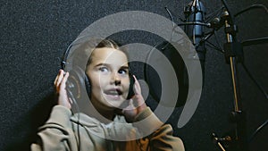 Teen girl in headphones singing into a microphone Professional audio studio music