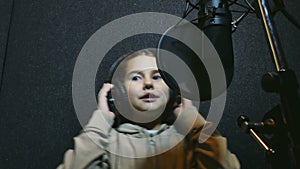 Teen girl in headphones singing into microphone Professional audio studio music