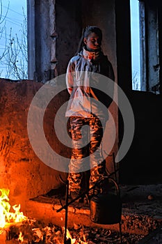 Teen girl heated by the fire in an abandoned house